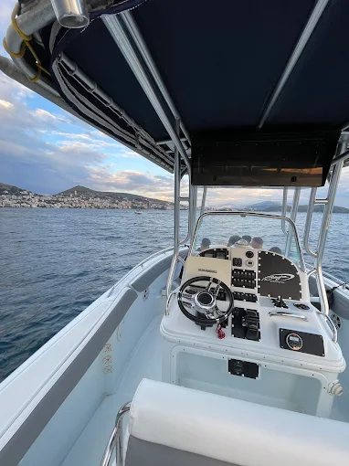 Helm and console of the Gloria Boat with Saranda hillside at dusk in the background